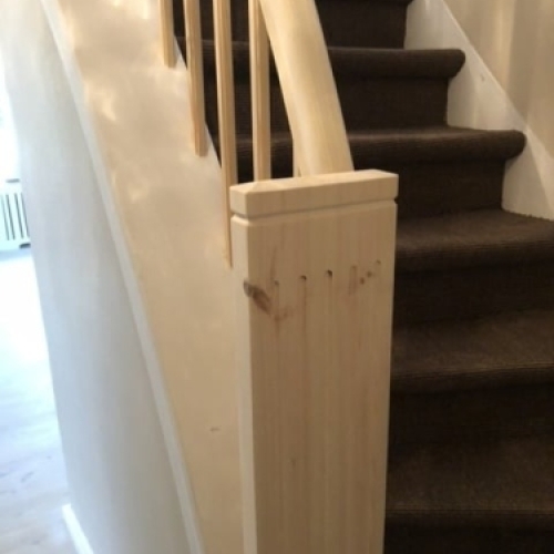 En klassisk trappe med hvidmalede balustre og et buet gelænder i mørkt træ, der giver et elegant udtryk.