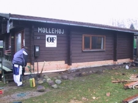 Et brunt bjælkehus som bliver renoveret med maling på Sjælland.